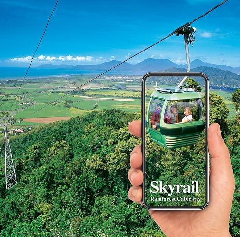 Hand holding phone with Skyrail gondola. Download interpretive app and audio guide
