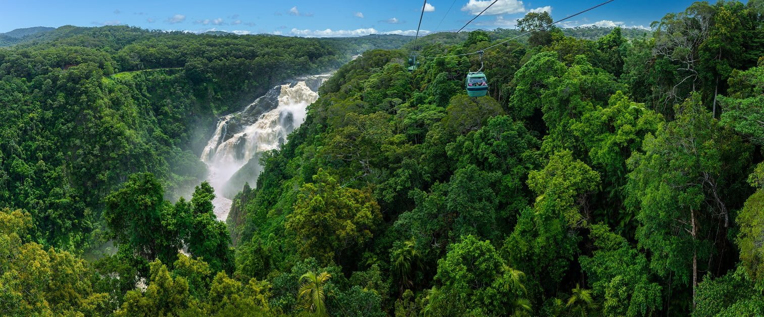 Skyrail gondola high over Barron falls with dense green tropical rainforest below