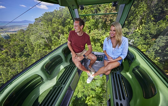 Couple sitting in Skyrail gondola with clear glass floor and expansive rainforest views