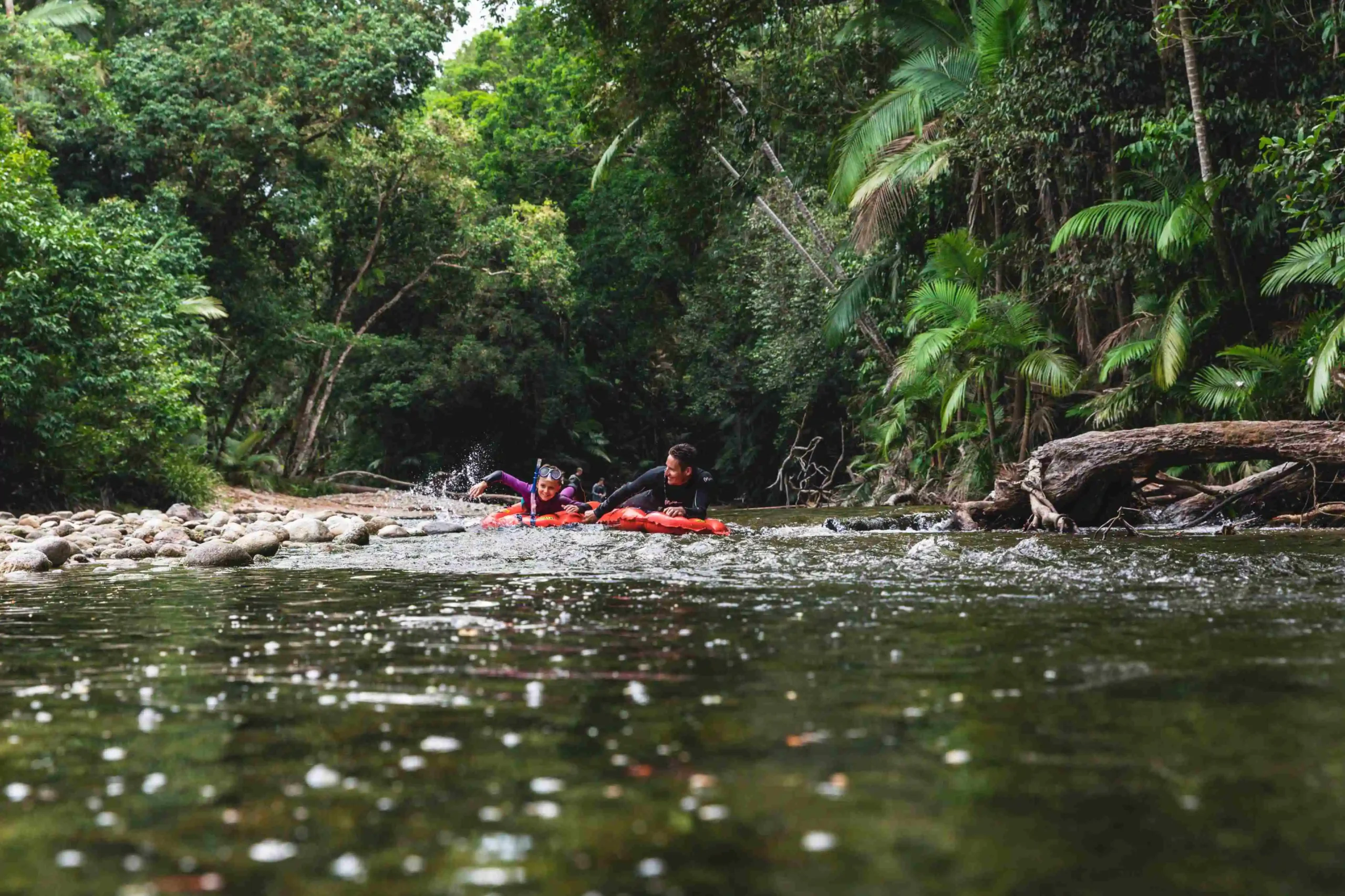 Two people on red air mattress floating down the Mossman Gorge