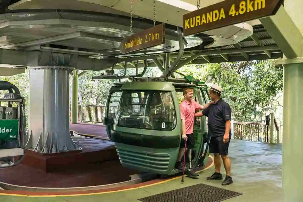Two men boarding a Skyrail gondola. Out there travel care