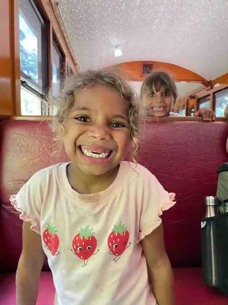 A girl smiles at the camera siting on the Kuranda Scenic Railway 