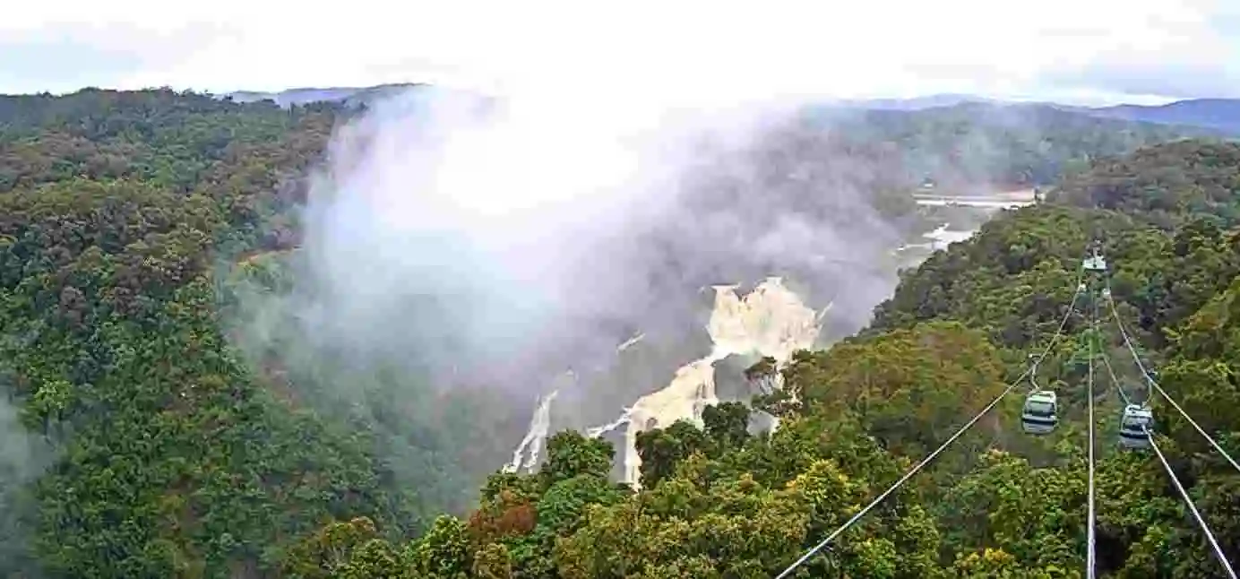 Skyrail Rainforest Cableway over the Wet Tropics rainforest with the Barron Falls in view and mist rising.
