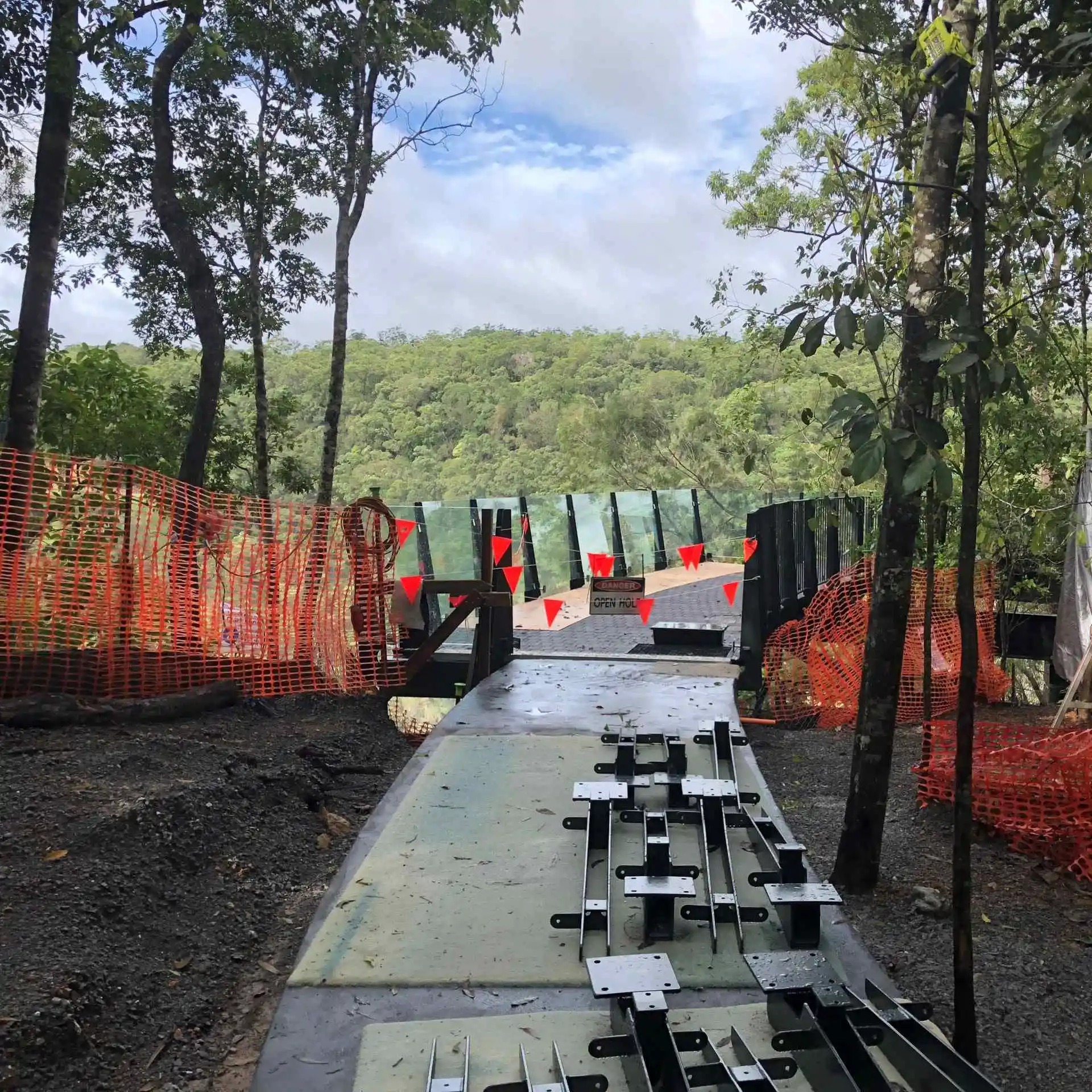 Lookoing down the glass pathway of The Edge Lookout at Skyrail with red cones and tape around it during construction 