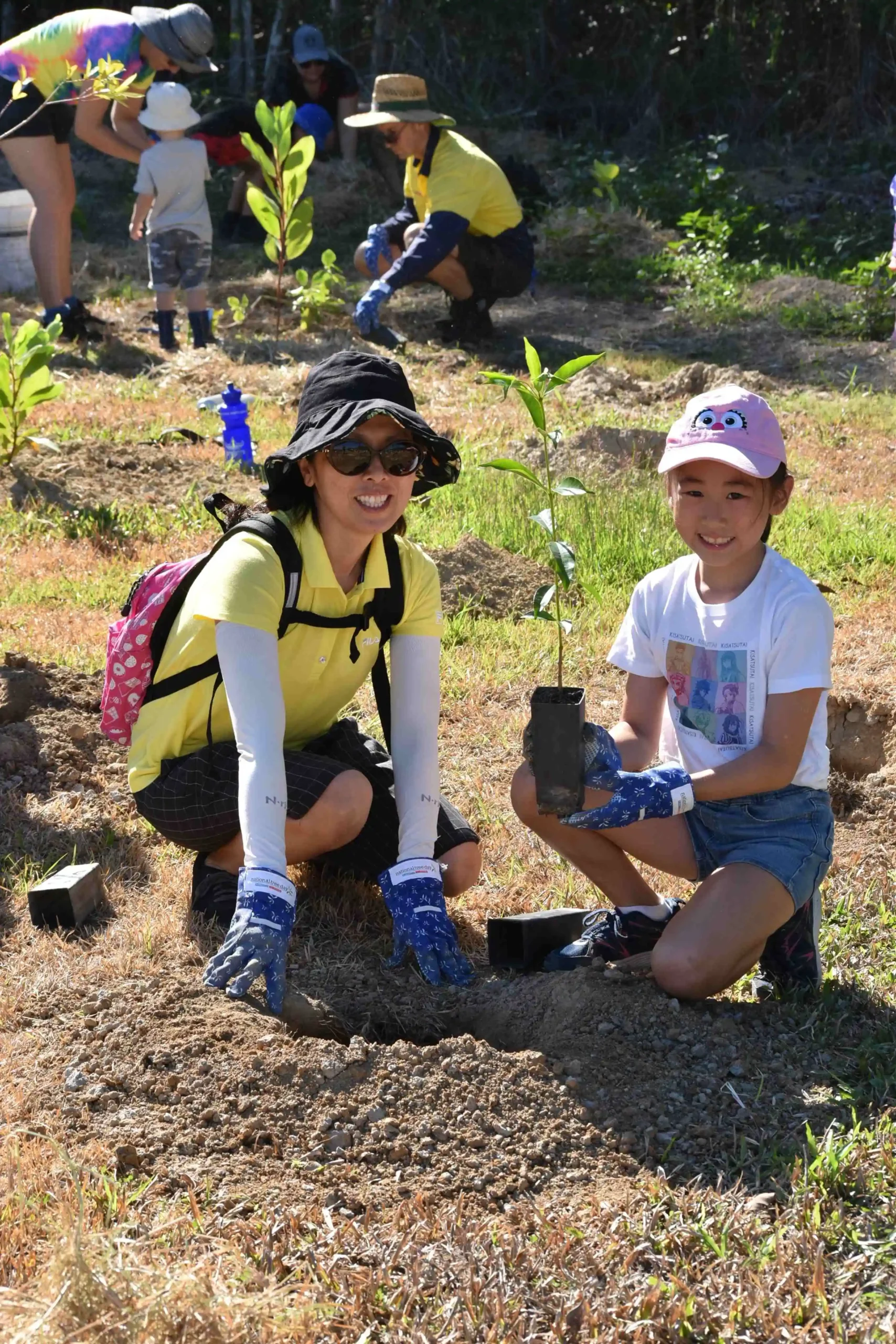 Mother and daughter planting a tree at Tropical Tree Day