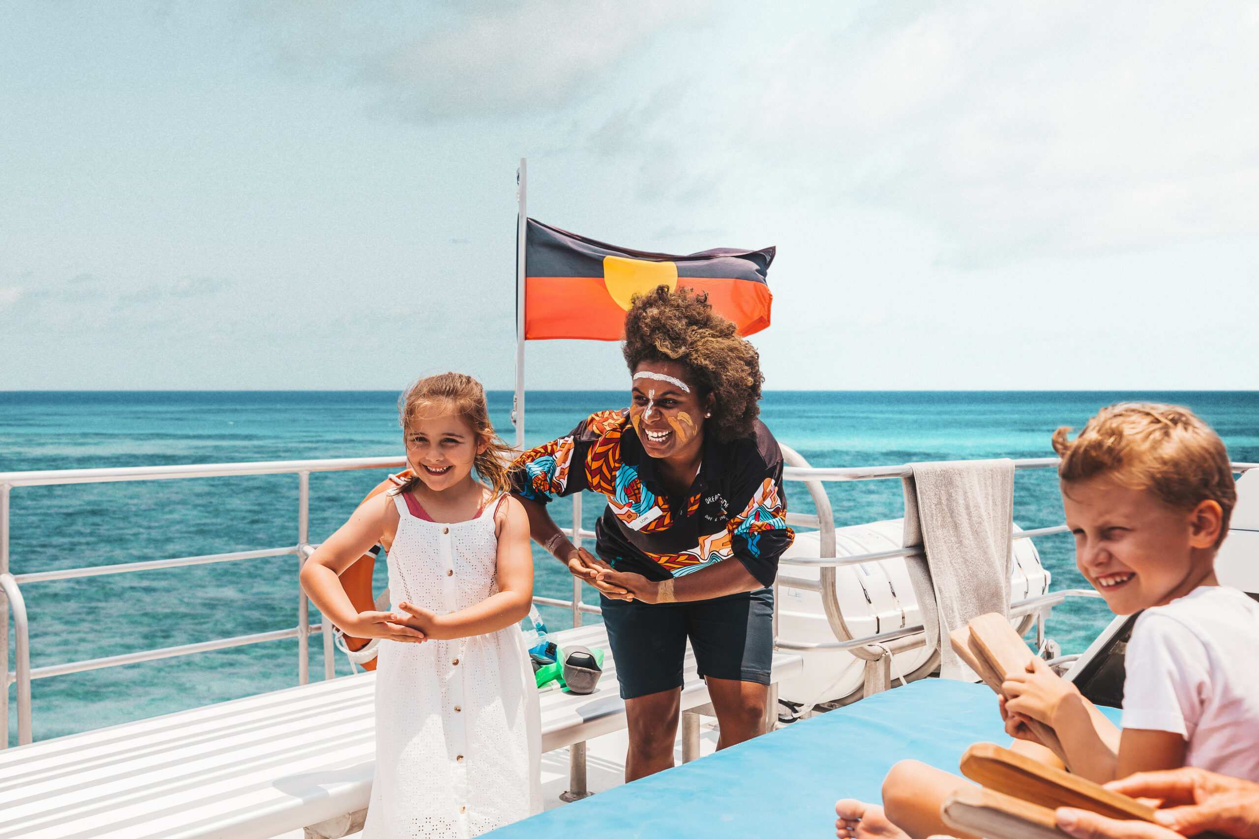 Indigenous guide teaching traditional dance to children on board Dreamtime Dive and Snorkel