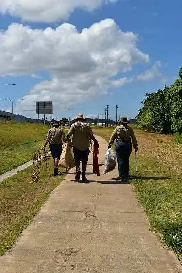 Skyrail Rangers walking with sacks in hand down a long pathway