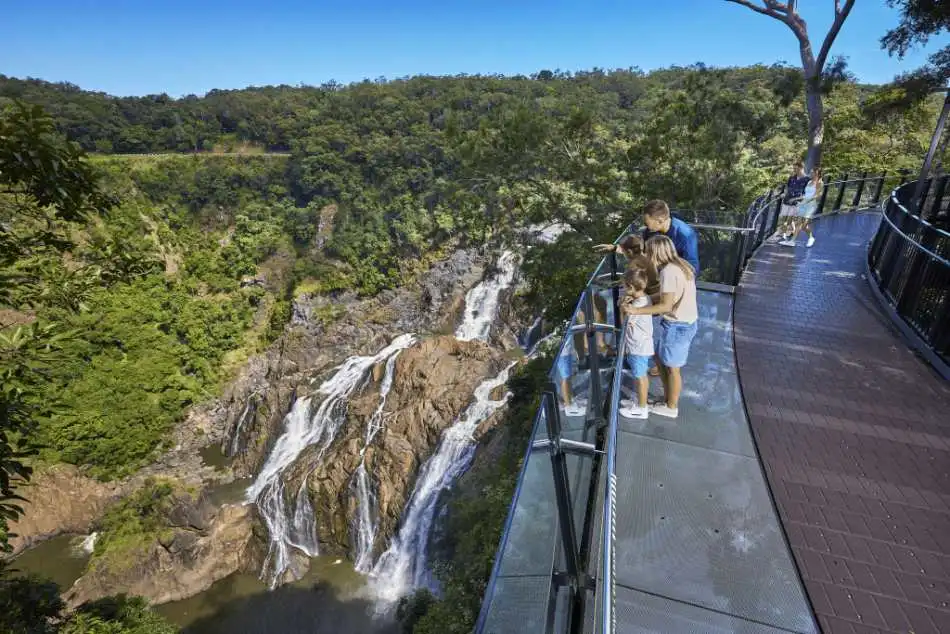 A man, woman and child stand at a glass lookout admiring the waterfall and deep gorge below