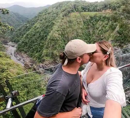 A male and female kiss at a glass lookout the the Barron Falls