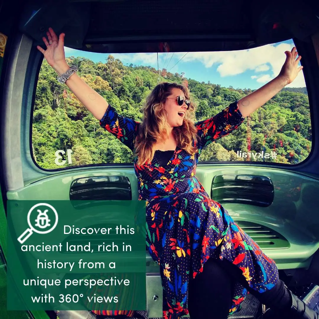 Girl wearing colourful dress with arms out in a gondola above tropical rainforest.