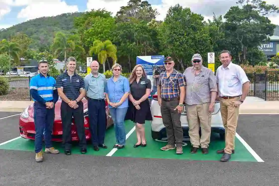 A group of people standing at the front of an electric vehicle charging station