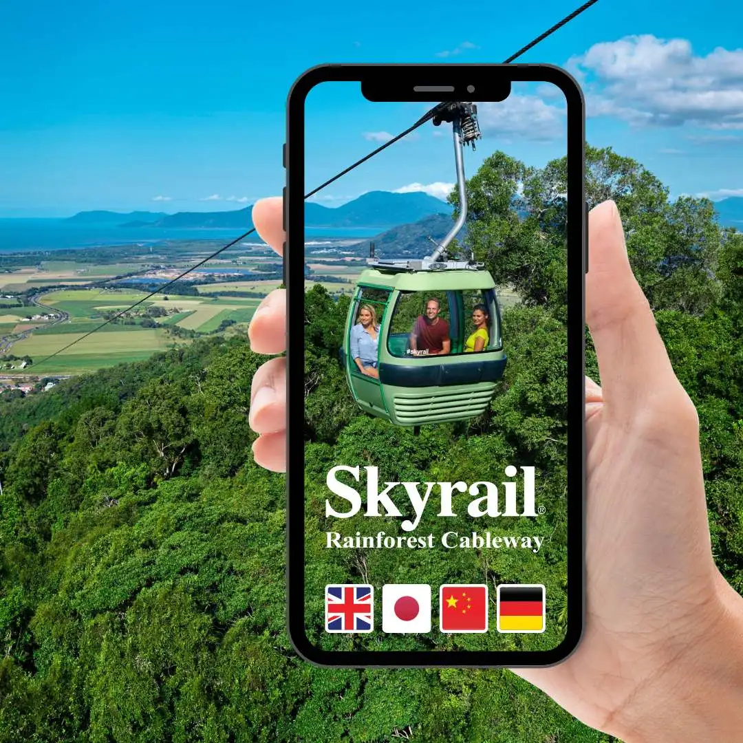 Hand holding a phone with Skyrail gondola and view across Cairns in the background. Available in English, Japanese, Chinese and German